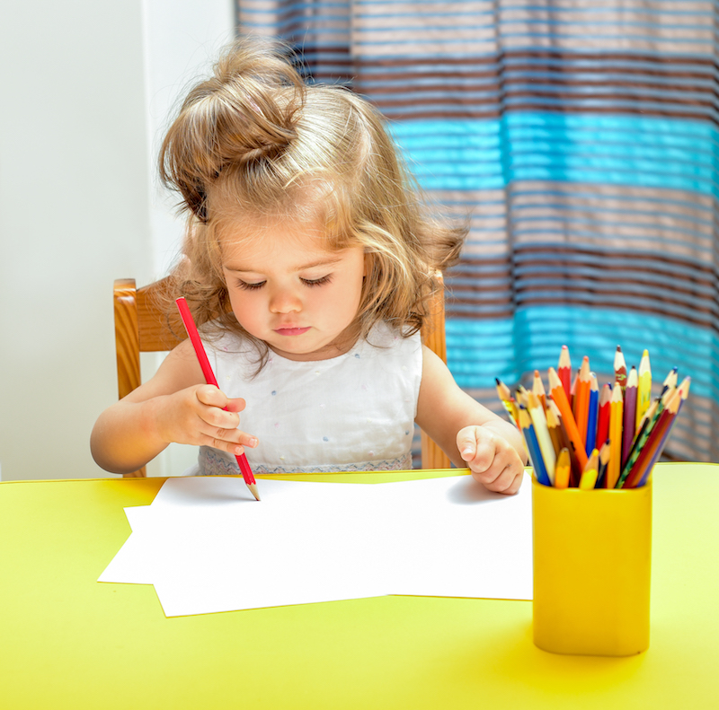 Little girl draws pencils. Interior of the room.